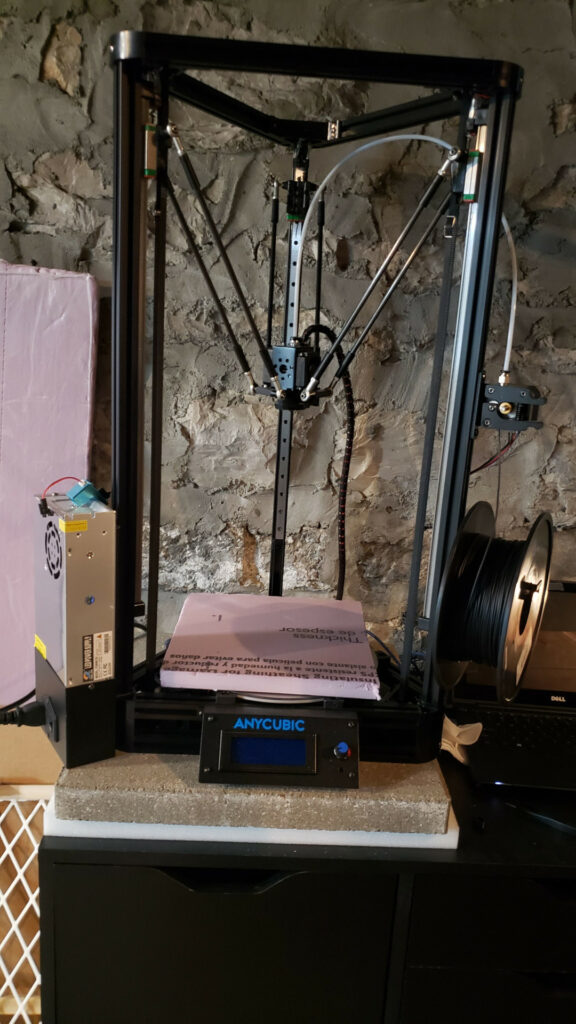 Photo of Anycubic Kossel on top of a concrete paver + upholstery foam isolation platform. 