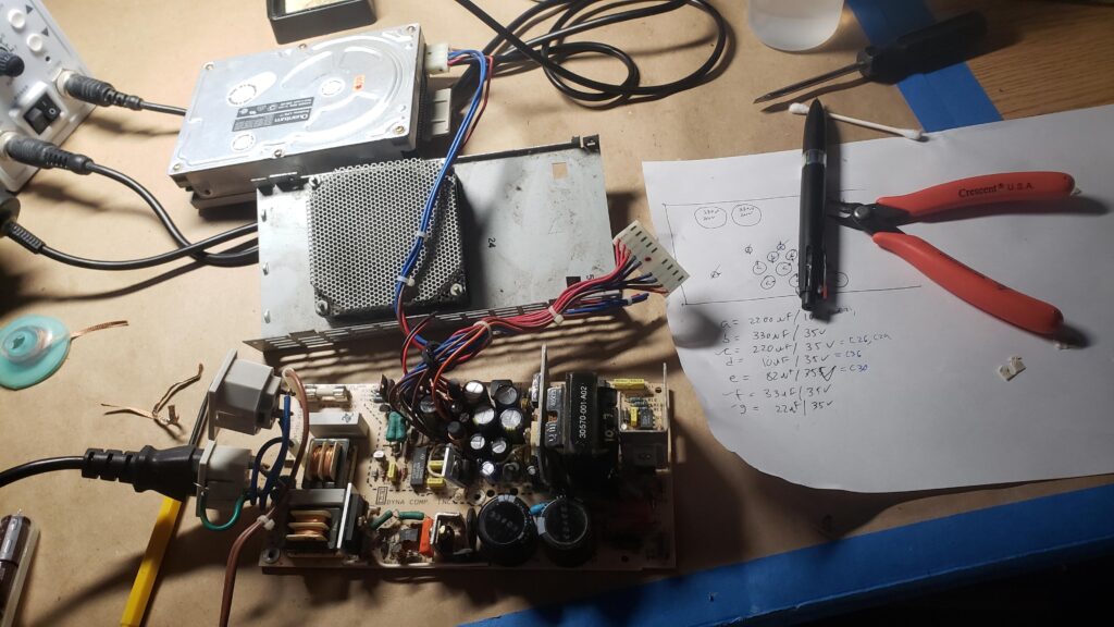 Sketchy tests setup with a gutted powered PSU, old HDD for load, and debris.