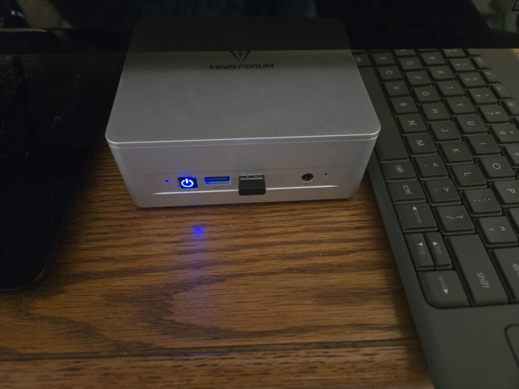 UM870Slim sitting under a TV, showing the light dimming film on the power button.
