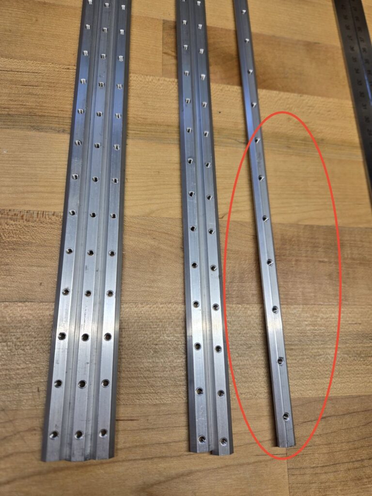 The fixing strips laid out, with the X strip visibly drilled off-center